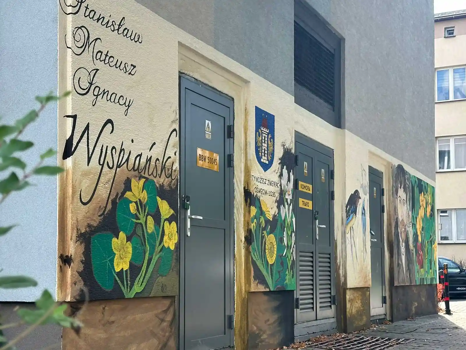 Mural z Wyspiańskim w Oświęcimiu – ujęcie wzdłuż ściany - NaszOświęcim - informacje i wydarzenia. Mural z Wyspiańskim przy ulicy Wyspiańskiego w Oświęcimiu widziany od strony kaligrafowanego imienia patrona, w głębi portret artysty