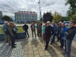 Spacer historyczny po dworcu w Oświęcimiu – początek trasy - NaszOświęcim - informacje i wydarzenia. Przewodnik z notatkami opowiada grupie uczestników spaceru historycznego na placu przy dworcu w Oświęcimiu