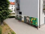 Mural ze Stanisławem Wyspiańskim na parterze bloku przy ulicy Wyspiańskiego w Oświęcimiu, widoczny z brukowanego przejścia między budynkami