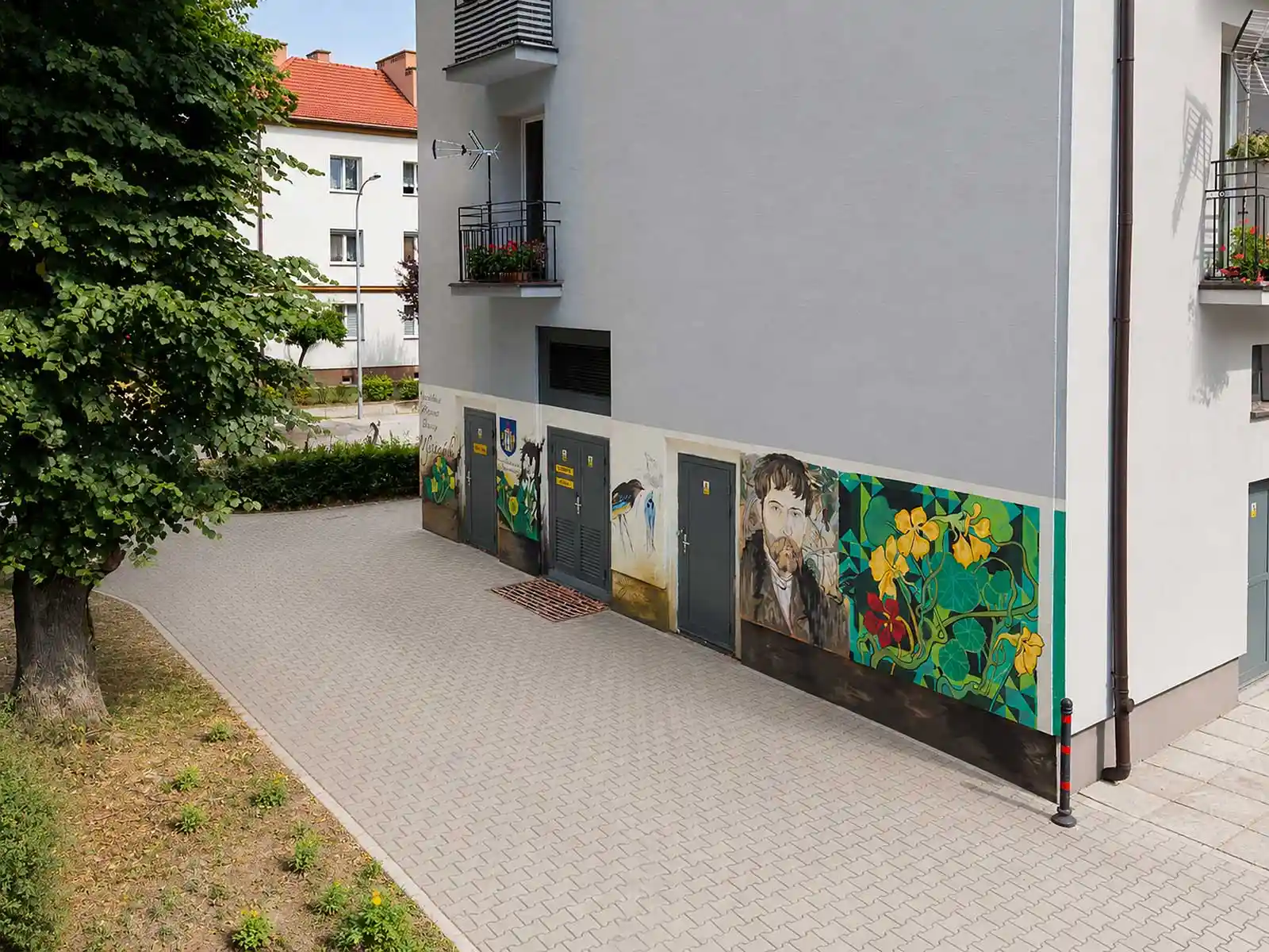 Mural z Wyspiańskim w Oświęcimiu – widok ogólny od strony osiedlowego przejścia - NaszOświęcim - informacje i wydarzenia. Mural ze Stanisławem Wyspiańskim na parterze bloku przy ulicy Wyspiańskiego w Oświęcimiu, widoczny z brukowanego przejścia między budynkami